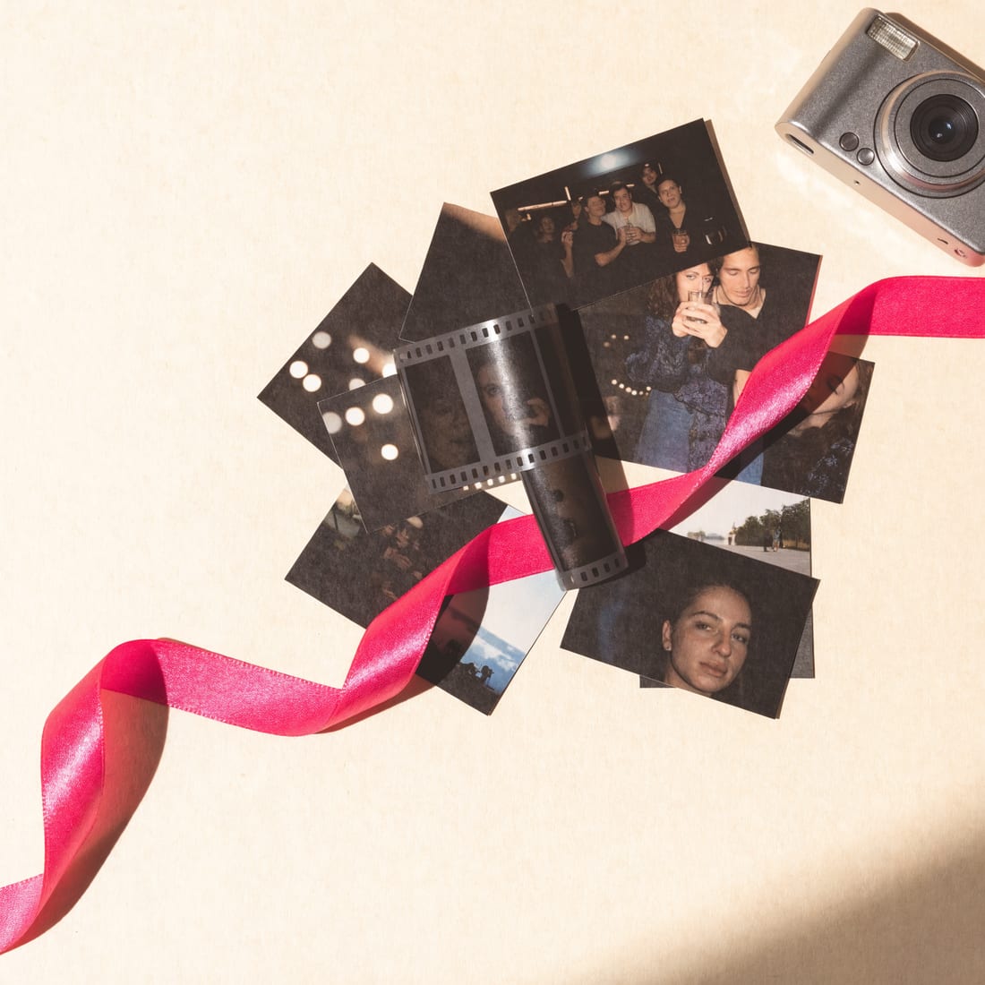 A stack of printed digicam snapshots and a strip of film on cream paper
